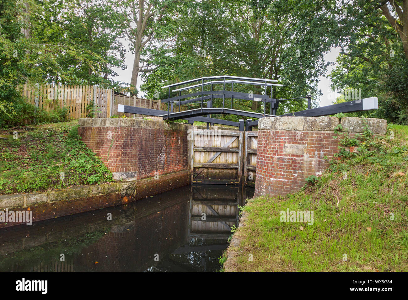Tipico pound serratura con pareti di mattoni e cancelli in legno sul Basingstoke Canal e la strada alzaia Knaphill, Woking, Surrey, Inghilterra sudorientale, REGNO UNITO Foto Stock