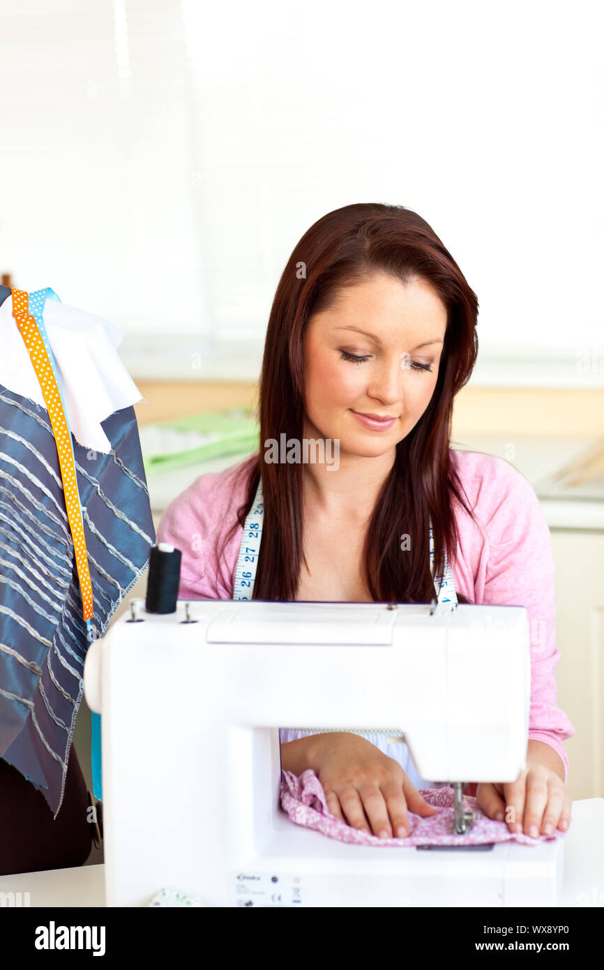 Concentrato donna caucasica la cucitura a casa in cucina Foto Stock