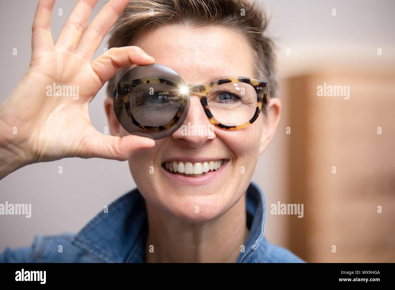 Donna con gli occhiali guardando attraverso il vetro colorato Foto Stock