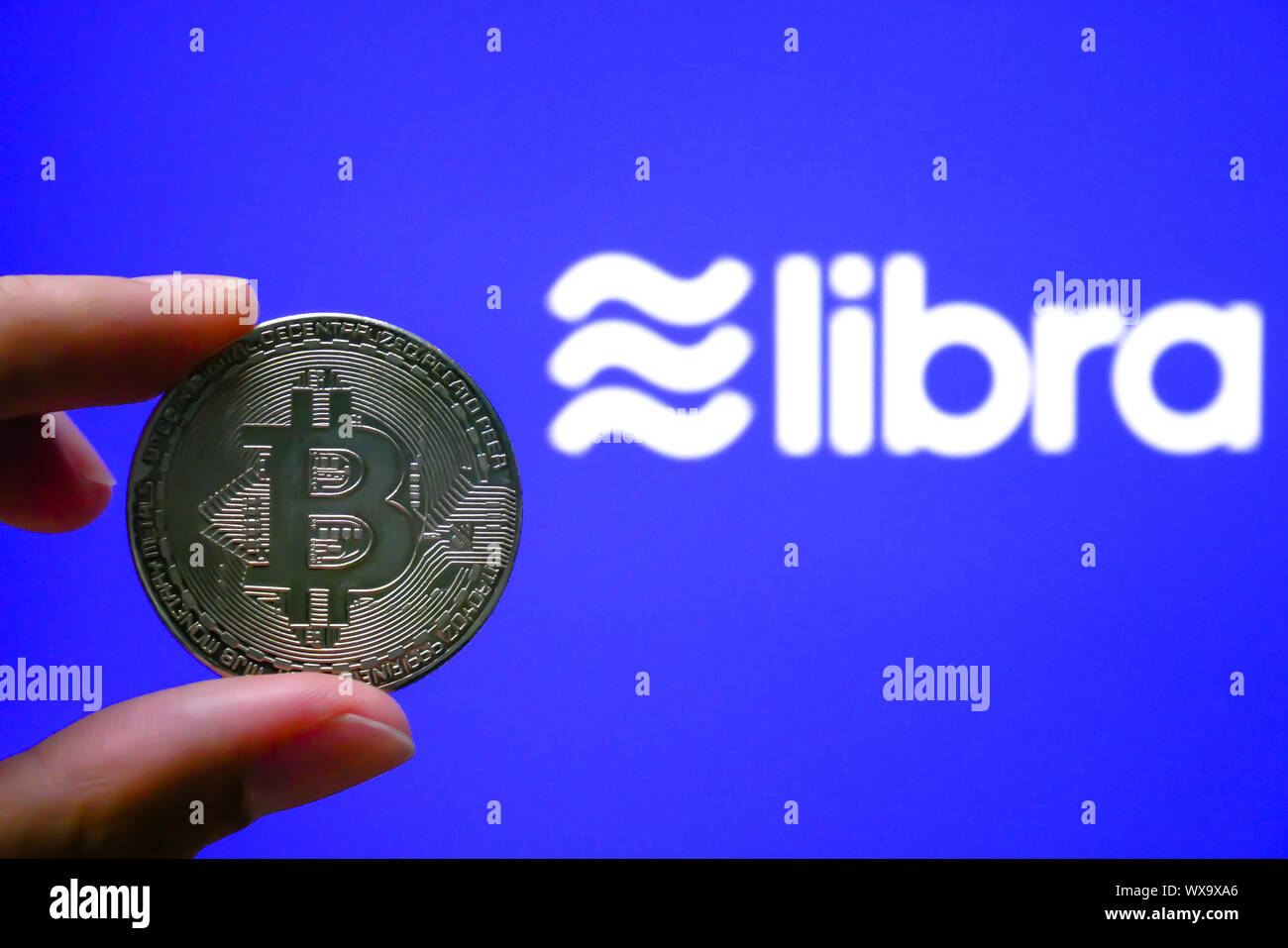 BANGKOK, Tailandia - 20 agosto 2019: Bitcoin sta tenendo a portata di mano wth un consentite blockchain valuta digitale proposto da Facebook. isolato su blu Foto Stock
