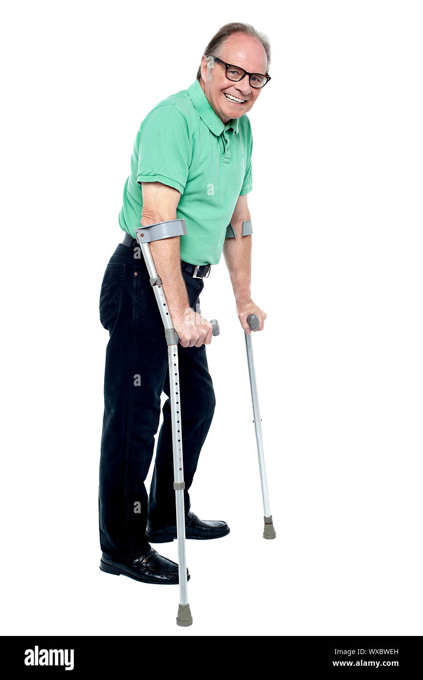 Uomo anziano a piedi con aiuto di stampelle. Il recupero dagli incidenti. Foto Stock