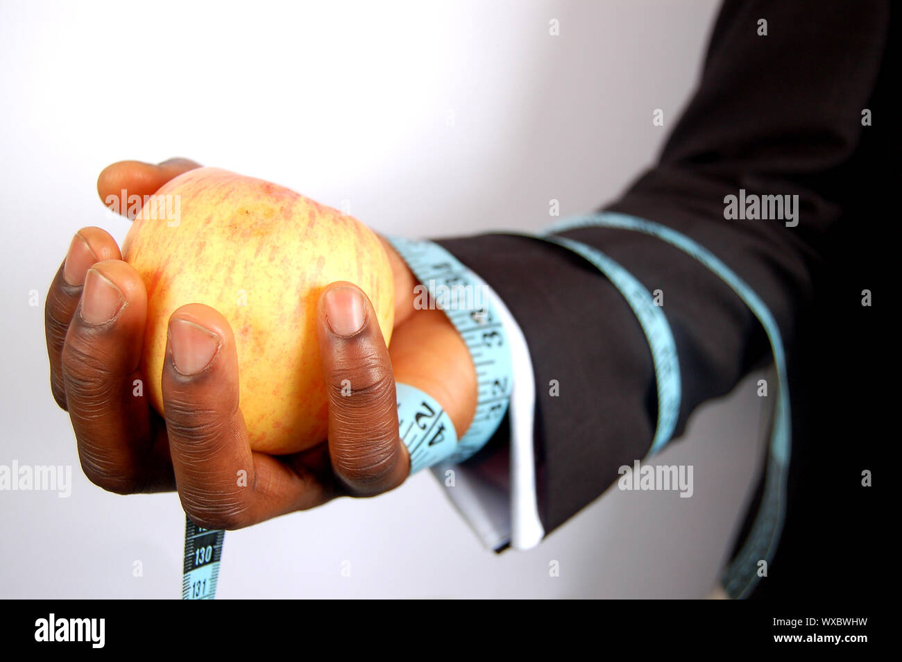 Si tratta di una immagine di un imprenditore in possesso di un apple, legata con un nastro di dieta. Questa è una metafora per la dieta, business, ecc Foto Stock