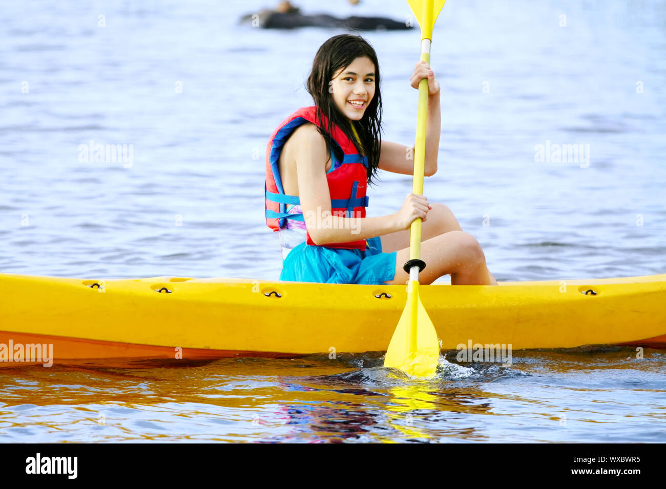 Teen girl in giallo kayak sul lago Foto Stock