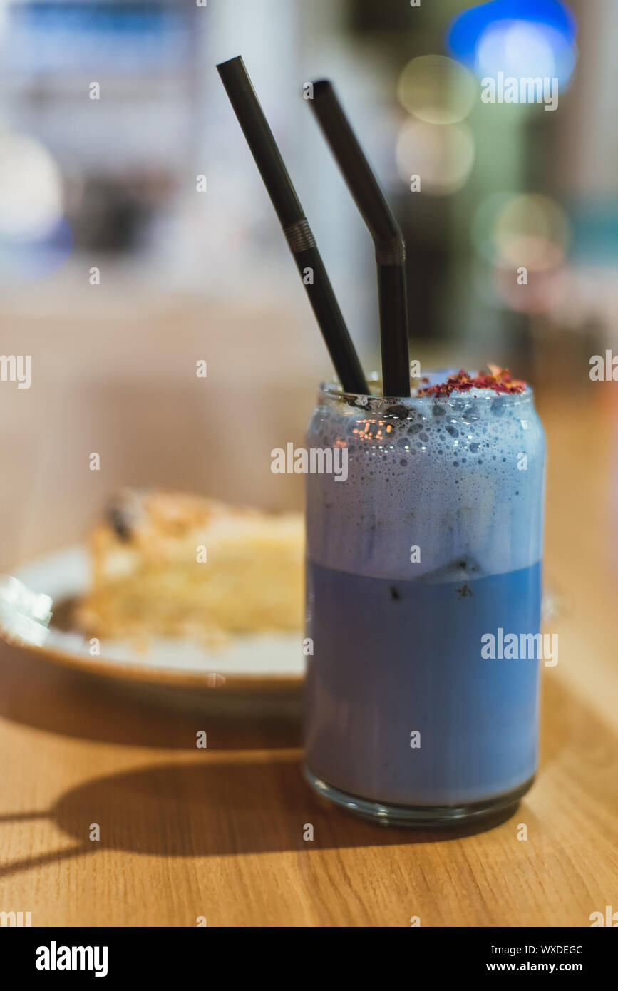 Un drink dal blu corrisponde in una caffetteria. Una sana e corretta costosi tè cinese con una fetta di torta su un tavolo di legno. Foto di stile di vita. Foto Stock