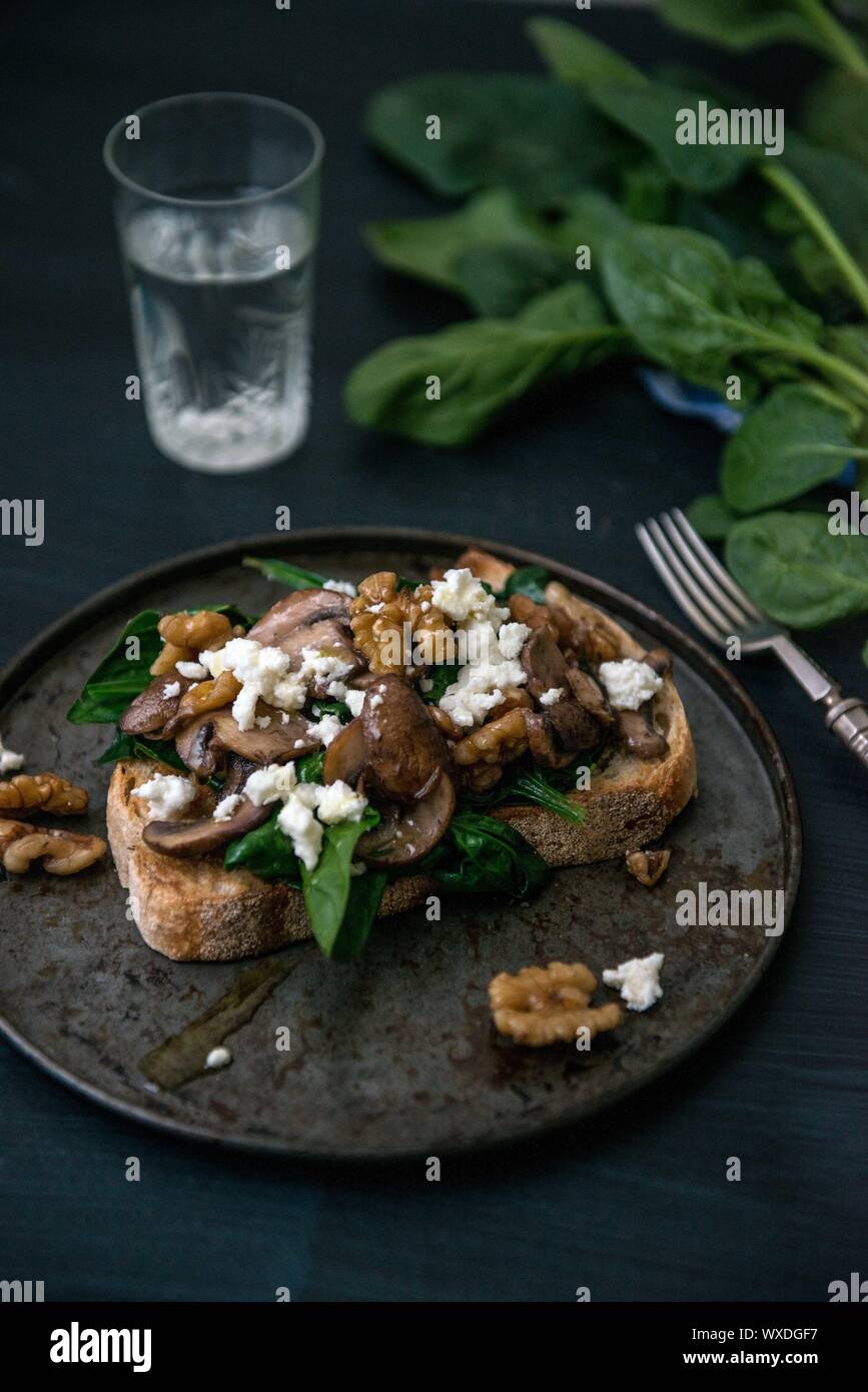 Moody cibo fotografia di funghi, feta e spinaci su pane tostato Foto Stock