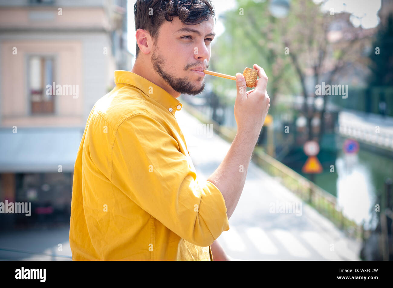 Giovane uomo tubazione di fumare sul balcone Foto Stock