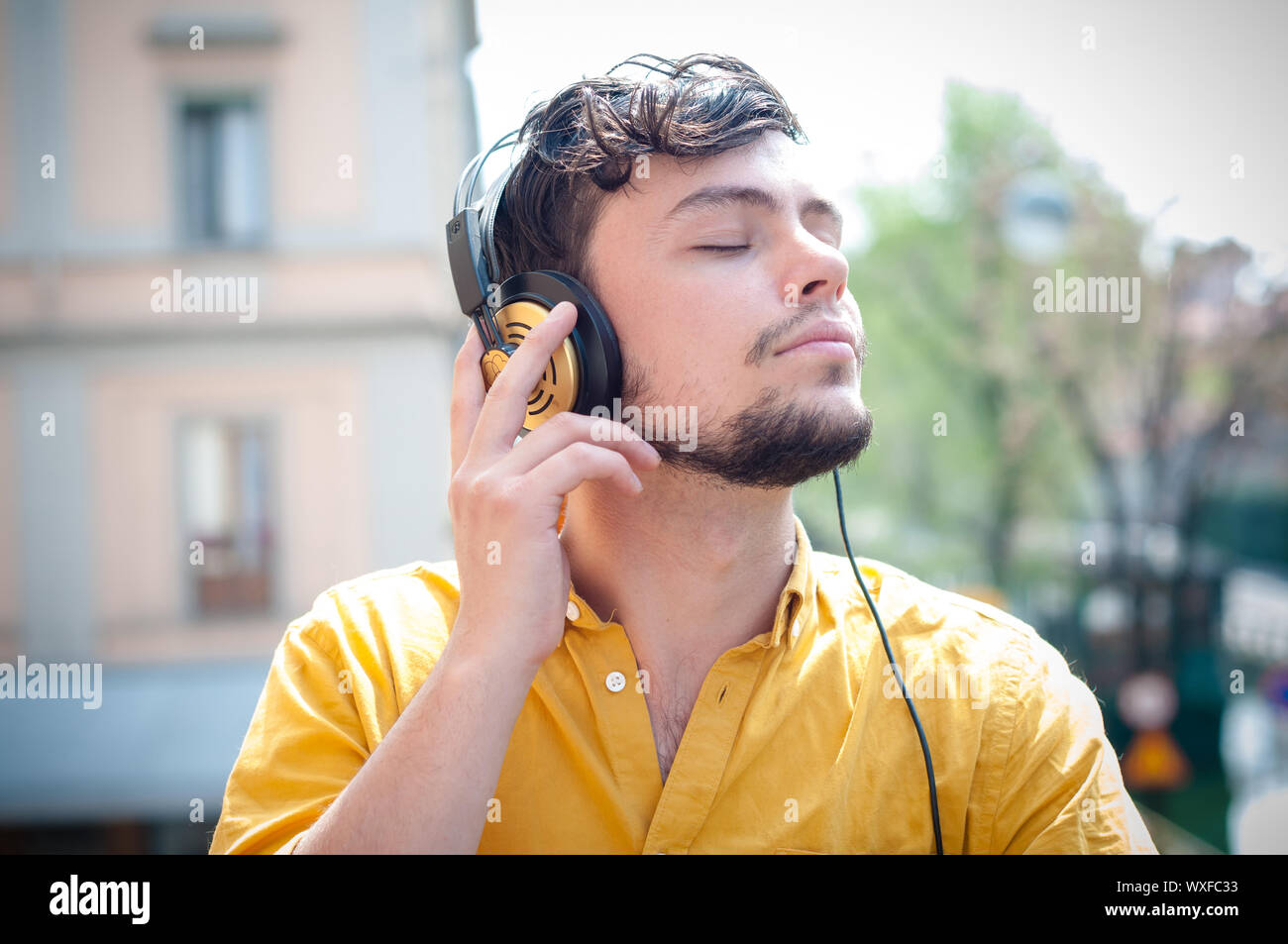 Hipster giovane uomo ascoltare musica sul balcone Foto Stock