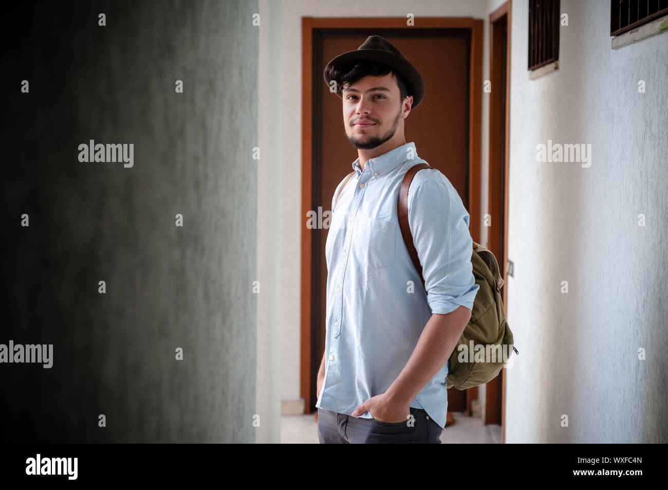 Hipster giovane uomo che pongono in un corridoio Foto Stock