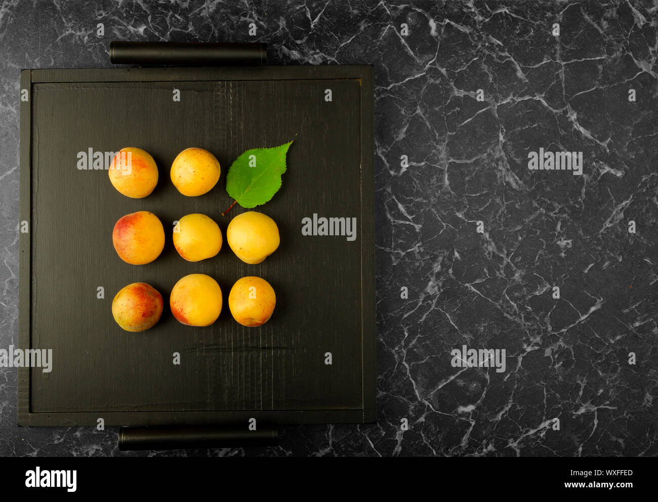 Albicocche mature giacente sul Tray nero su sfondo scuro Foto Stock