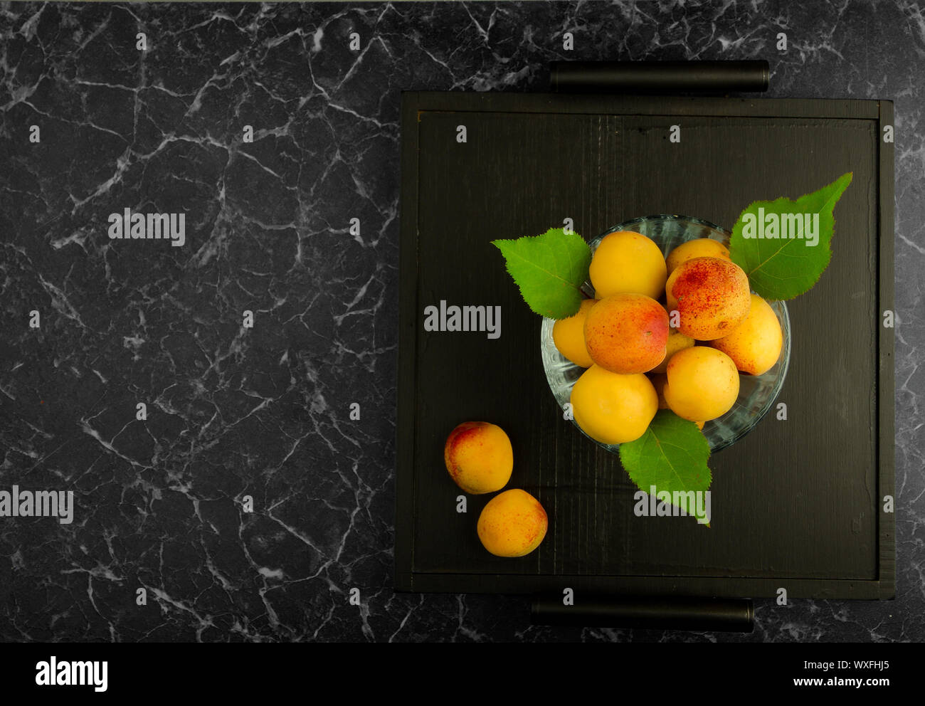 Albicocche mature giacente sul Tray nero su sfondo scuro Foto Stock