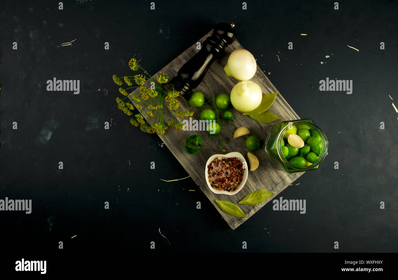 Verdure pomodori e spezie sulla scheda. Cipolle Aglio pomodori spezie aneto grigio sul pannello di legno su un rilievo di superficie in pietra. Foto Stock