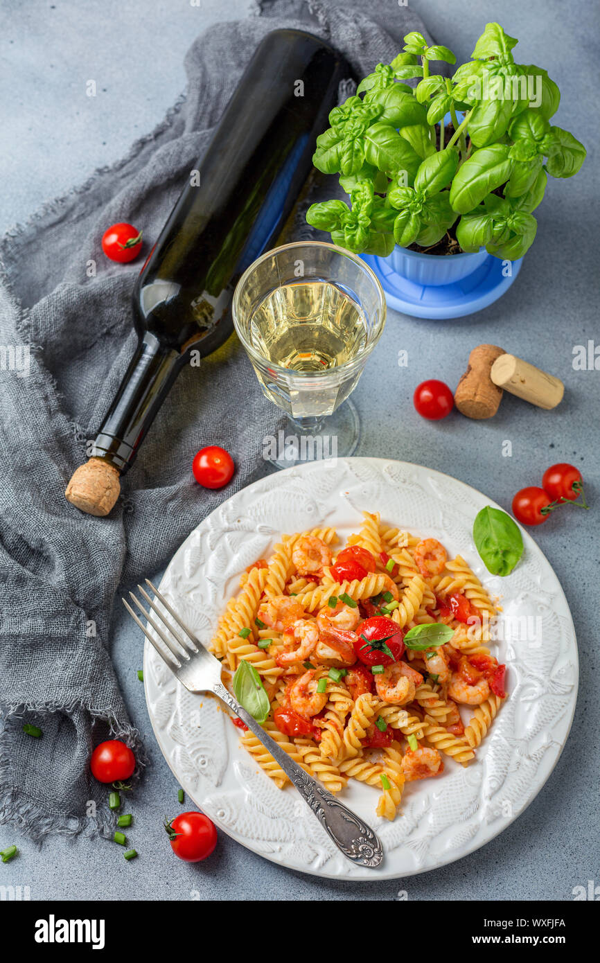 Pomodoro pastа adibiti alla pesca di gamberetti e un bicchiere di vino bianco. Foto Stock