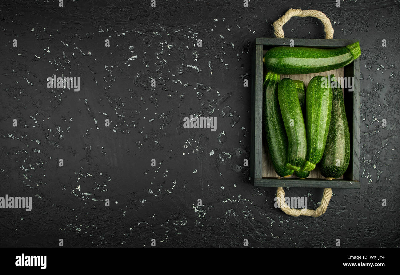 Fresco verde di zucchina al buio su un tavolo. La vista dall'alto. Copia dello spazio. Foto Stock