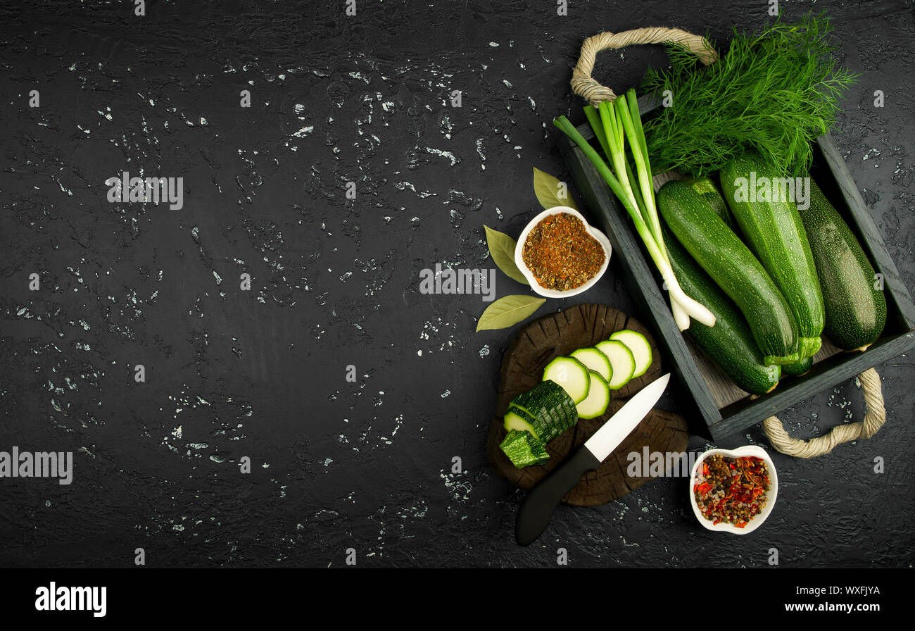 Fresco verde di zucchina al buio su un tavolo. La vista dall'alto. Copia dello spazio. Foto Stock