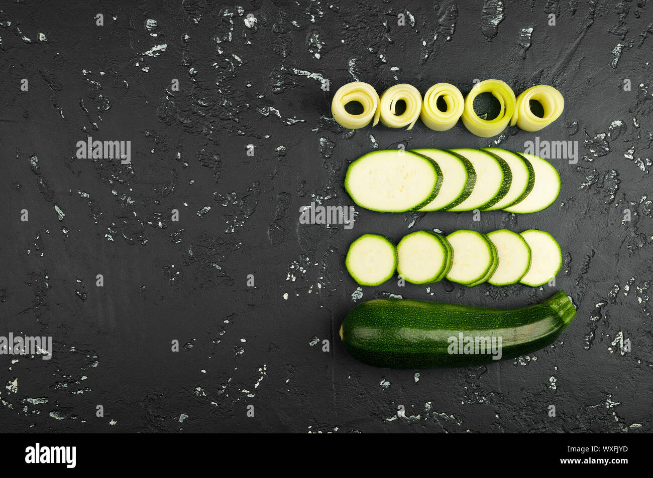 Fresco verde di zucchina al buio su un tavolo. La vista dall'alto. Copia dello spazio. Foto Stock