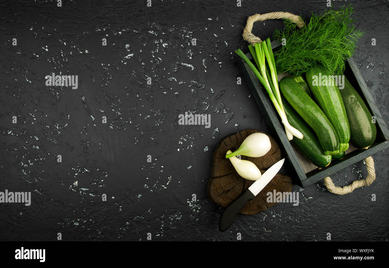 Fresco verde di zucchina al buio su un tavolo. La vista dall'alto. Copia dello spazio. Foto Stock