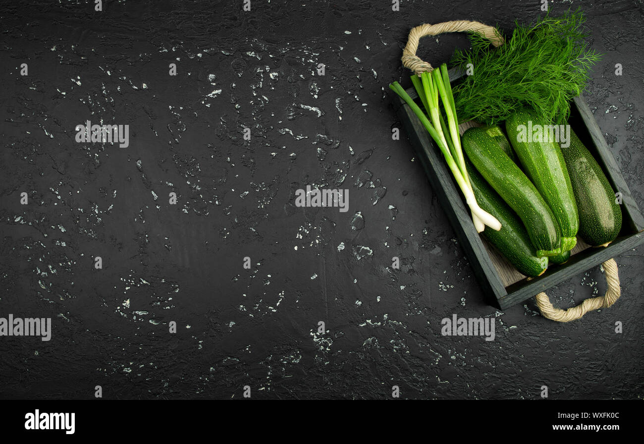 Fresco verde di zucchina al buio su un tavolo. La vista dall'alto. Copia dello spazio. Foto Stock