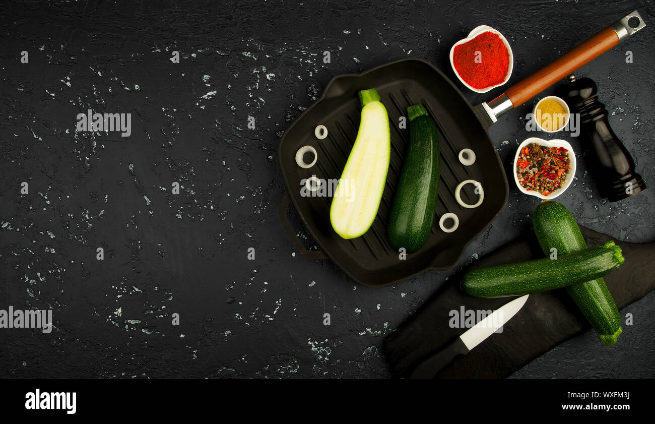 Fresco verde le zucchine in una padella al buio su un tavolo. La vista dall'alto. Copia dello spazio. Foto Stock