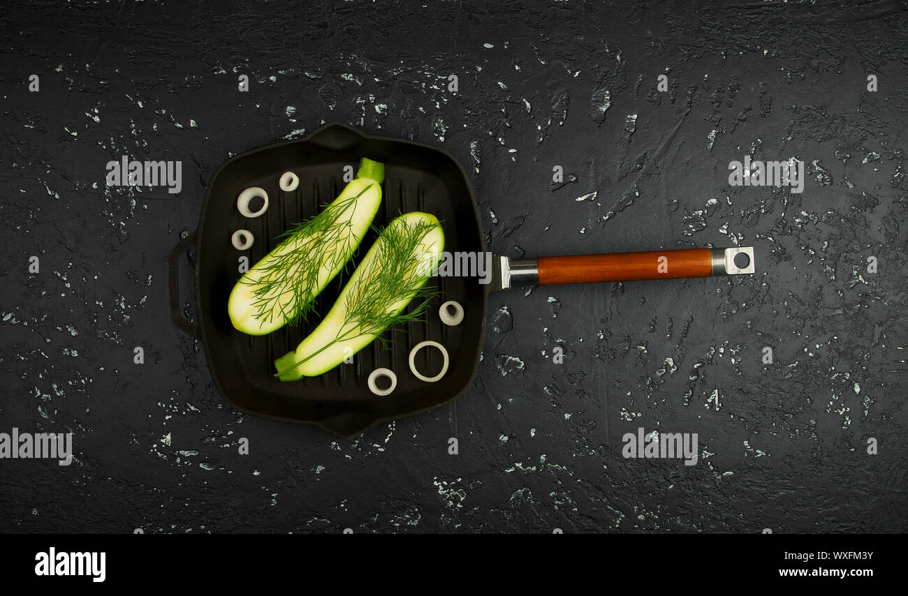 Fresco verde le zucchine in una padella al buio su un tavolo. La vista dall'alto. Copia dello spazio. Foto Stock