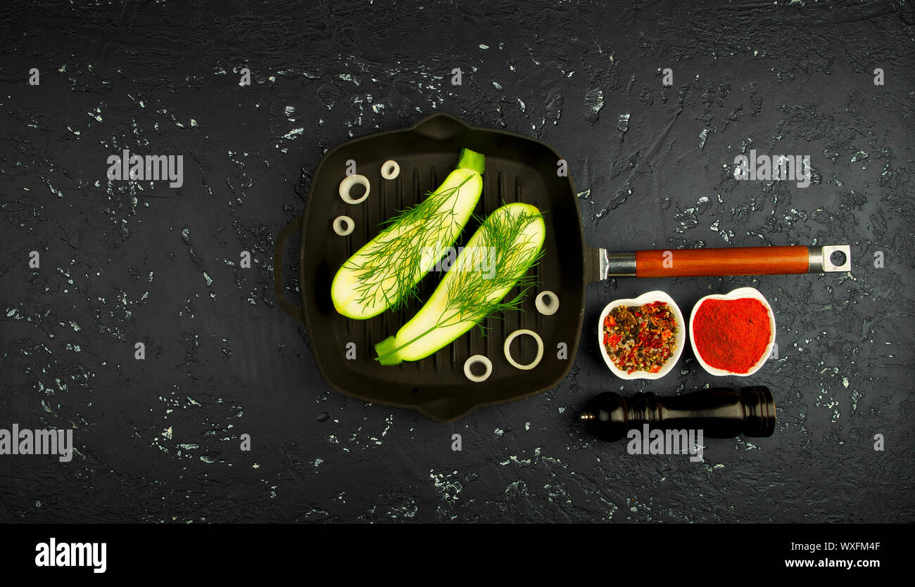 Fresco verde le zucchine in una padella al buio su un tavolo. La vista dall'alto. Copia dello spazio. Foto Stock