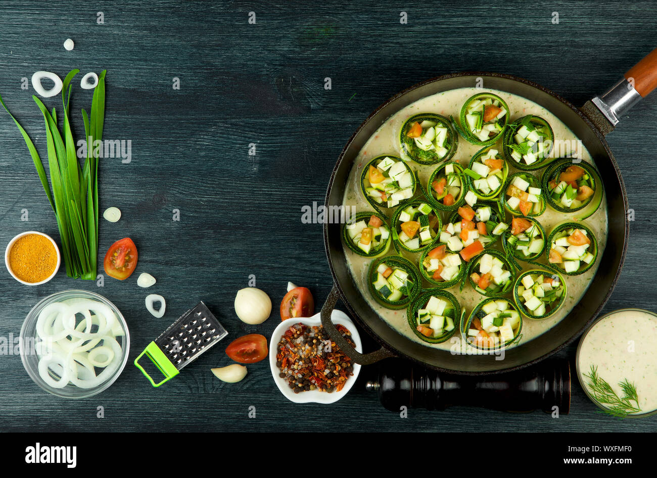 Zucchine in background. Giovani fritto le zucchine tagliate a fette in una padella su uno sfondo scuro. La vista dall'alto. Spazio di copia Foto Stock