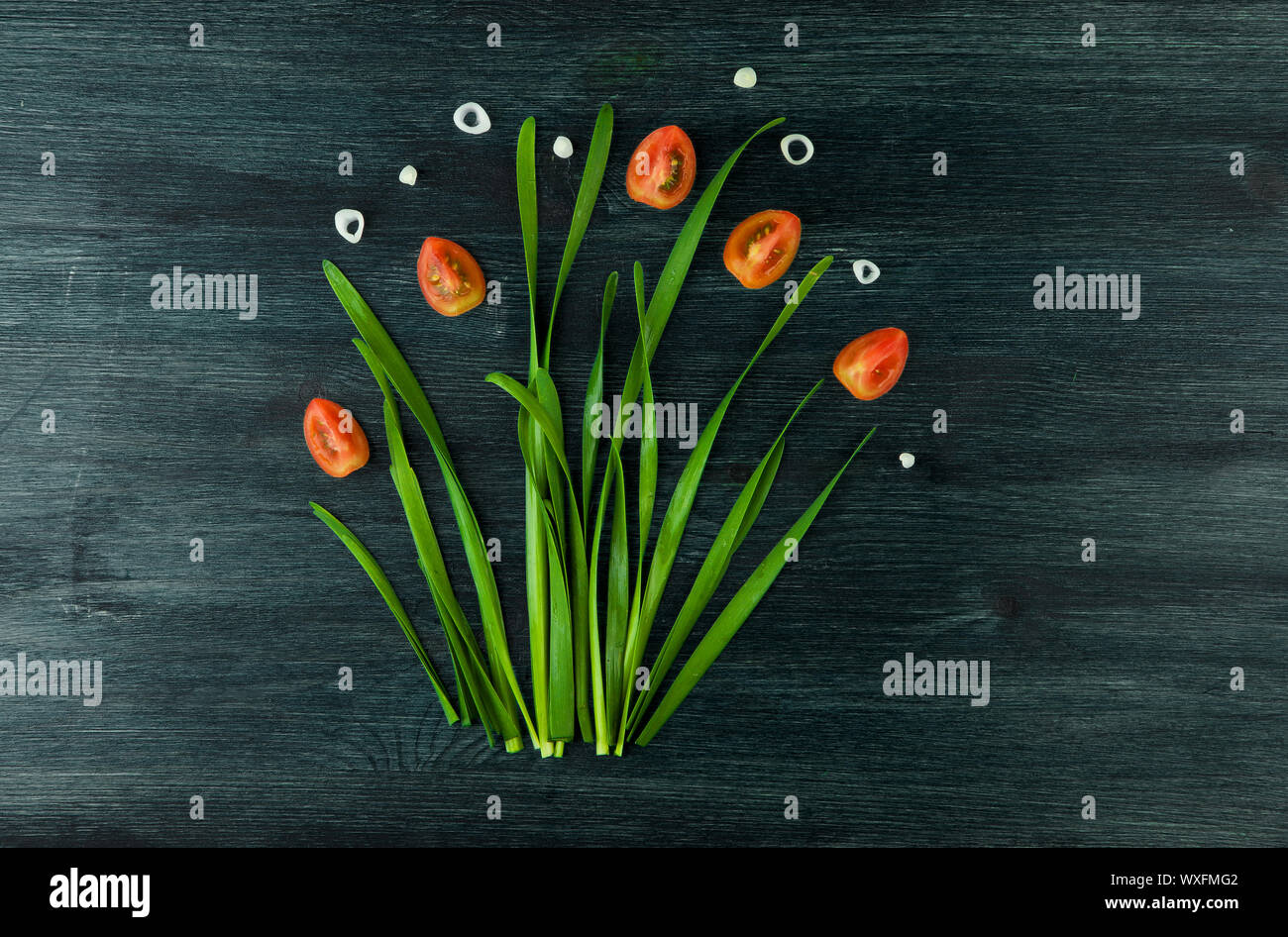 Arco sullo sfondo. Arco verde delle cipolle, cipolle bianche e pomodoro su un forte piano di legno. Concetto di immagine vegetale. V Foto Stock