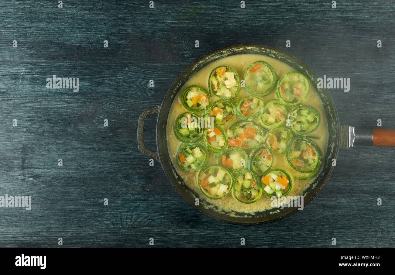 Zucchine in background. Giovani fritto le zucchine tagliate a fette in una padella su uno sfondo scuro. La vista dall'alto. Spazio di copia Foto Stock