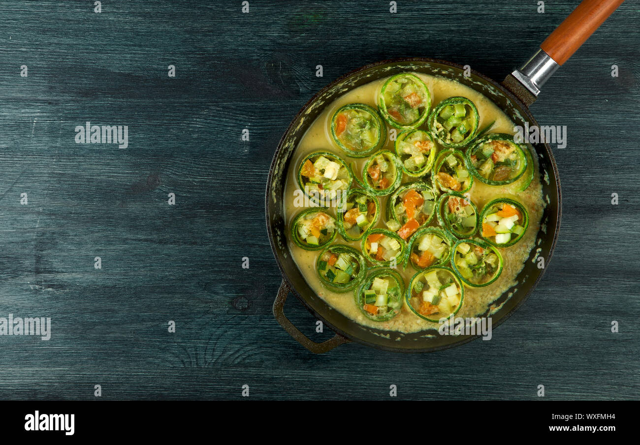 Zucchine in background. Giovani fritto le zucchine tagliate a fette in una padella su uno sfondo scuro. La vista dall'alto. Spazio di copia Foto Stock