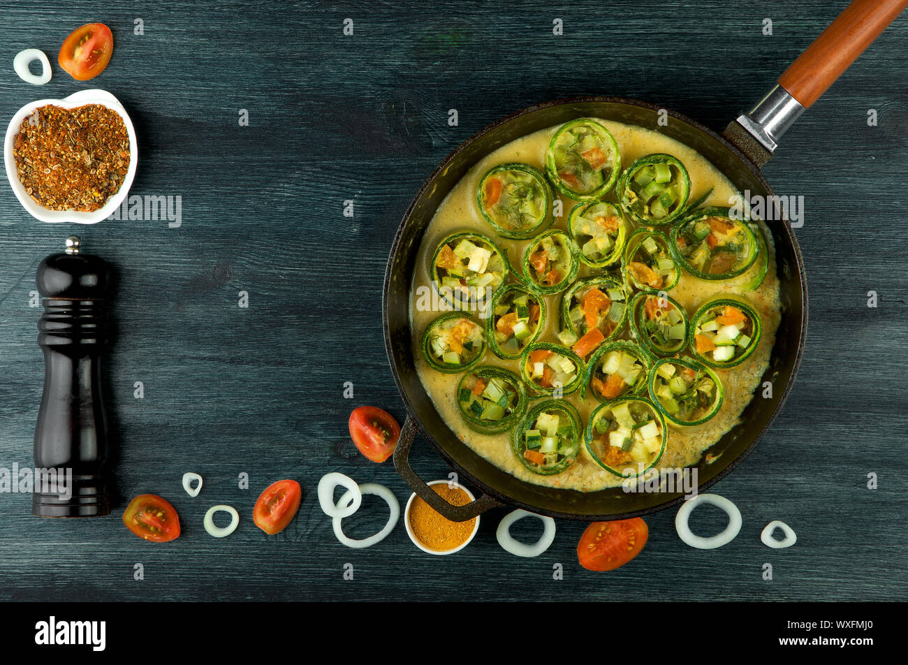 Zucchine in background. Giovani fritto le zucchine tagliate a fette in una padella su uno sfondo scuro. La vista dall'alto. Spazio di copia Foto Stock