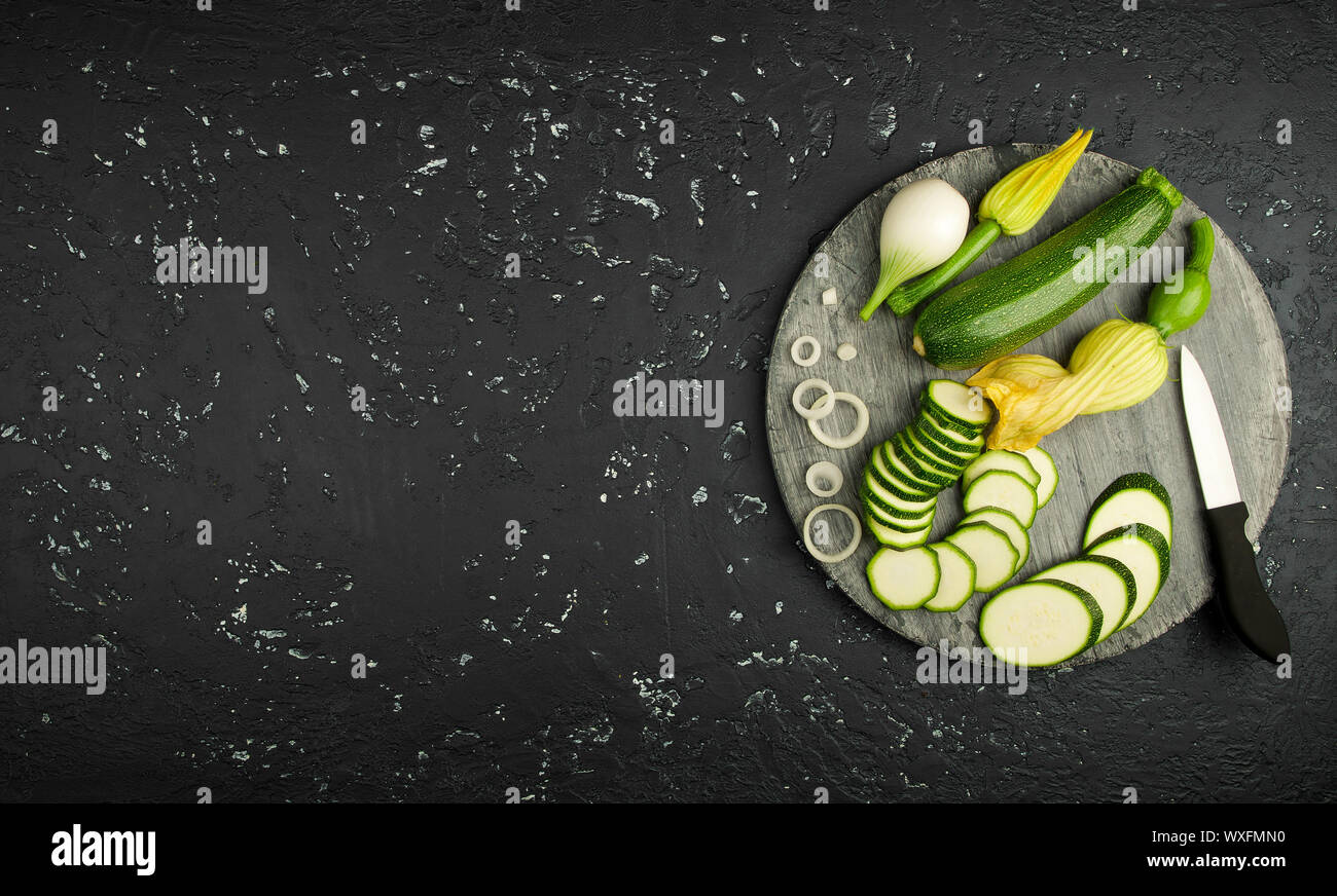 Fresco verde di zucchina al buio su un tavolo. La vista dall'alto. Copia dello spazio. Foto Stock