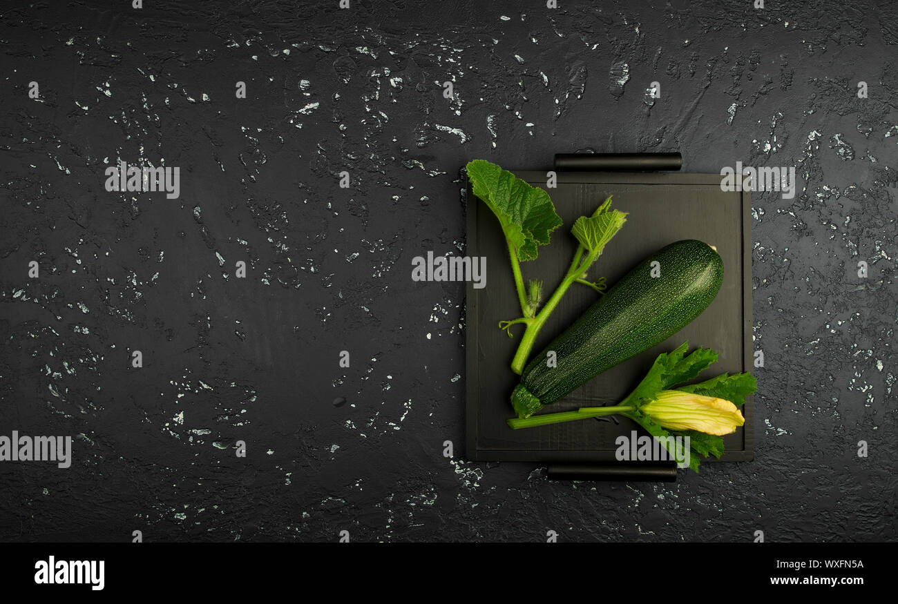 Fresco verde di zucchina al buio su un tavolo. La vista dall'alto. Copia dello spazio. Foto Stock