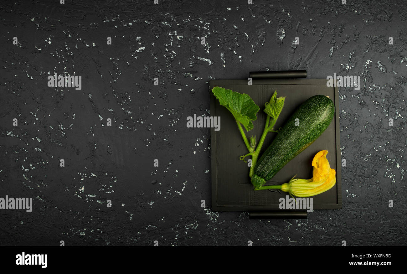 Fresco verde di zucchina al buio su un tavolo. La vista dall'alto. Copia dello spazio. Foto Stock