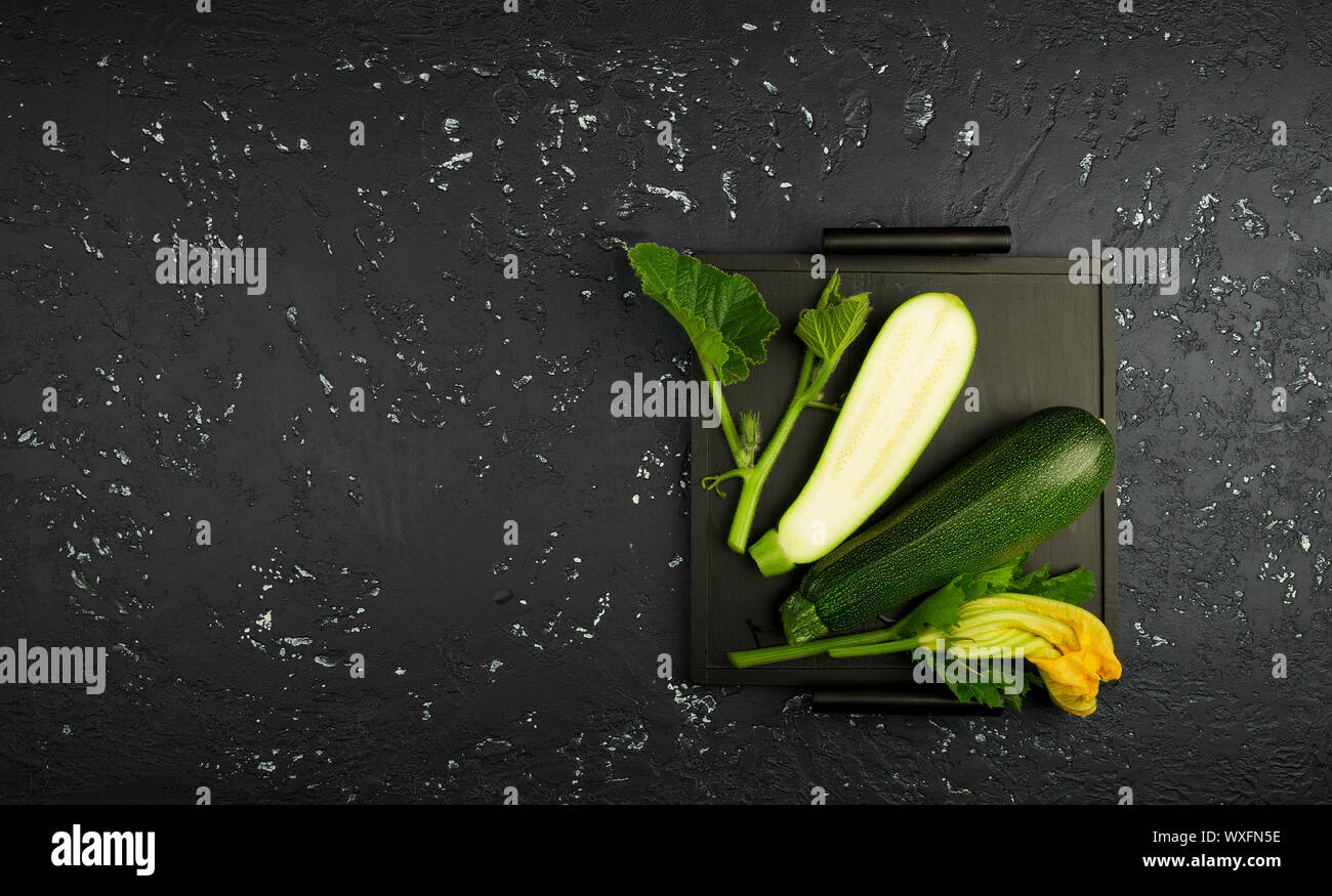 Fresco verde di zucchina al buio su un tavolo. La vista dall'alto. Copia dello spazio. Foto Stock