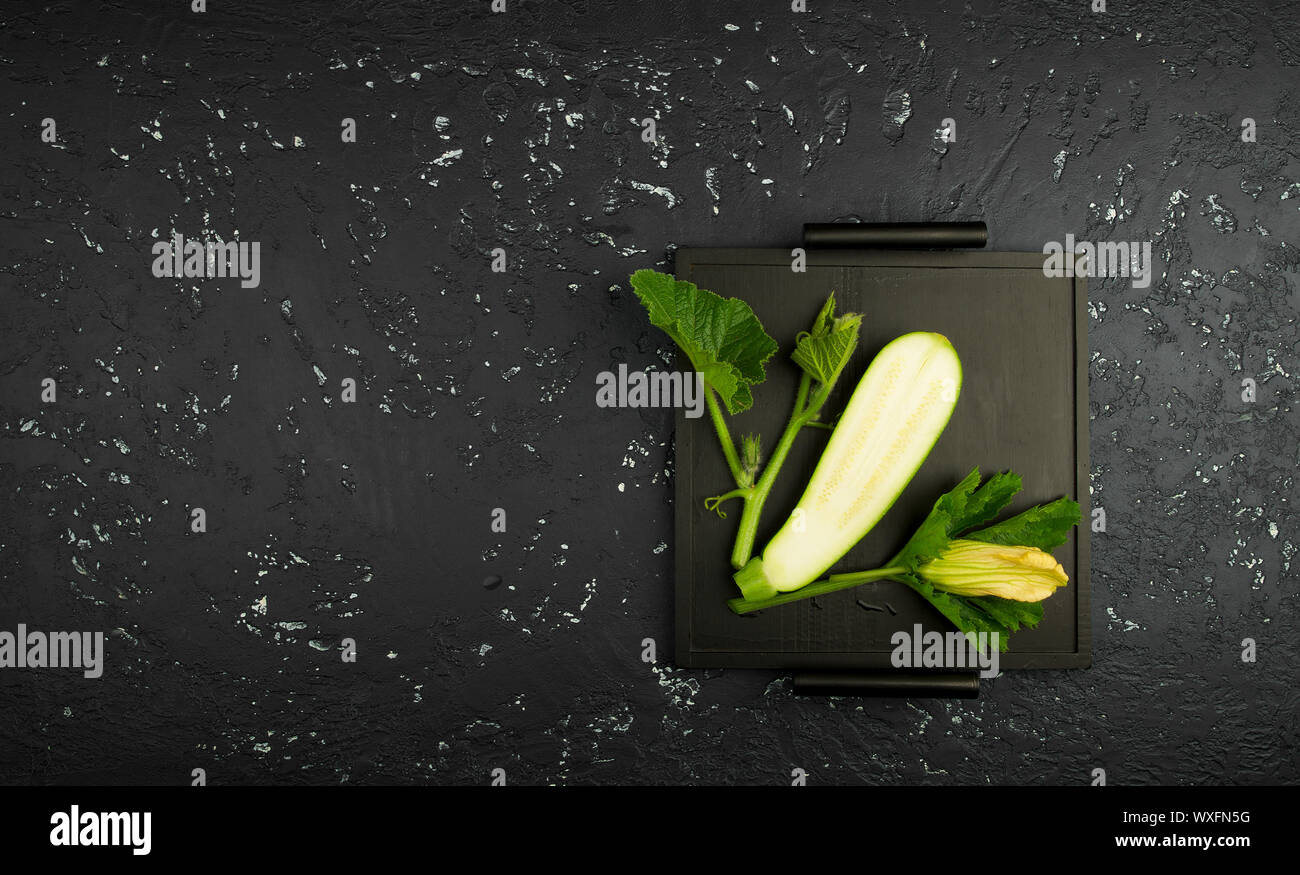 Fresco verde di zucchina al buio su un tavolo. La vista dall'alto. Copia dello spazio. Foto Stock