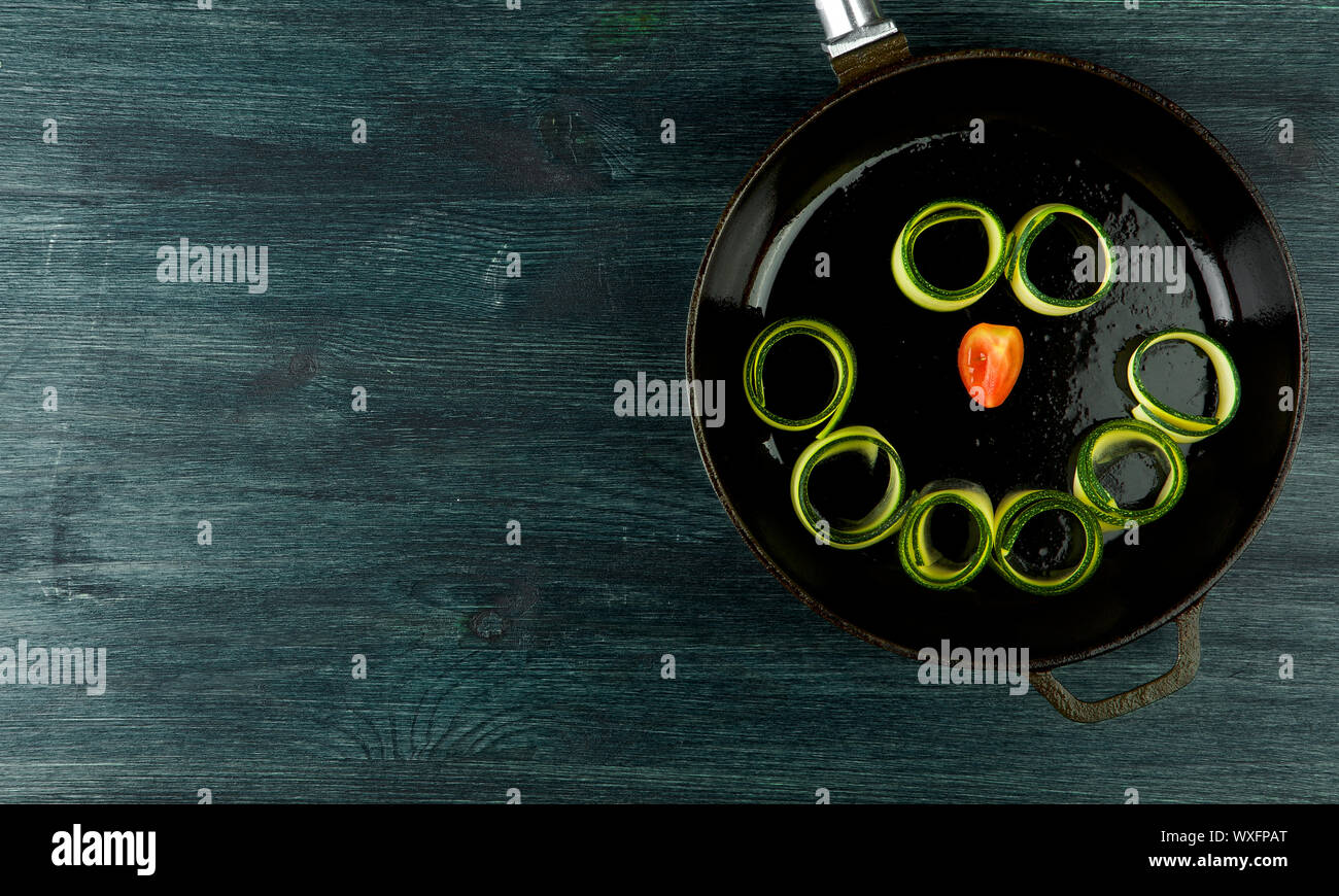 Zucchine in background. Giovani fritto le zucchine tagliate a fette in una padella su uno sfondo scuro. La vista dall'alto. Spazio di copia Foto Stock
