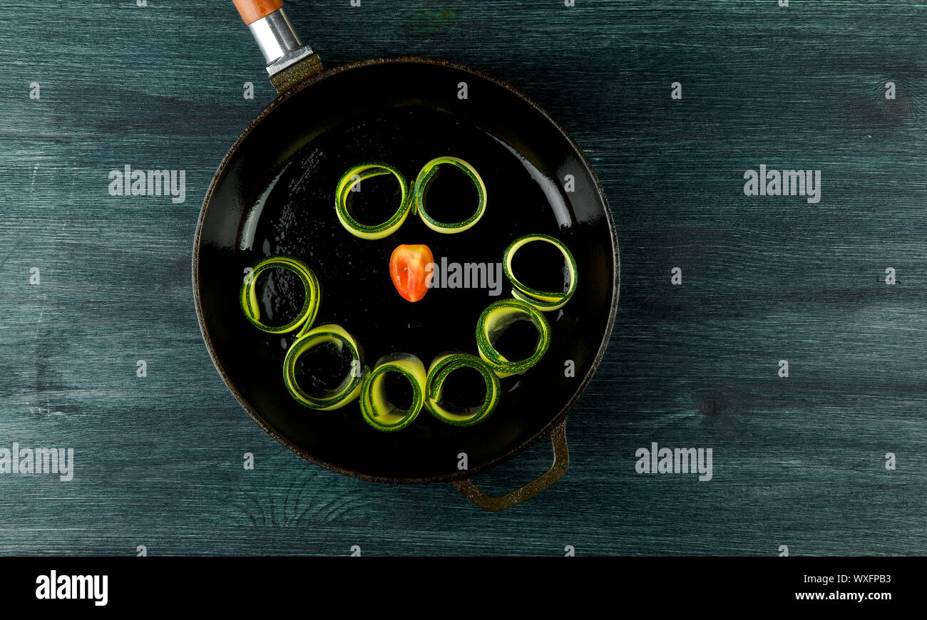 Zucchine in background. Giovani fritto le zucchine tagliate a fette in una padella su uno sfondo scuro. La vista dall'alto. Spazio di copia Foto Stock
