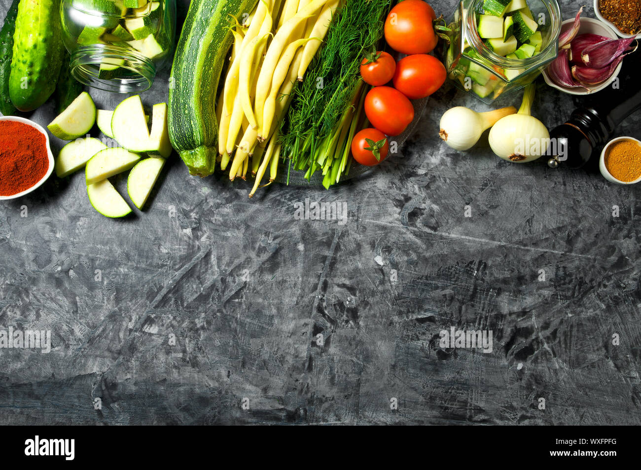 Verdure sullo sfondo. Ortaggi freschi (cetrioli, pomodori, cipolle, aglio, aneto, fagioli verdi) su sfondo grigio. A Foto Stock