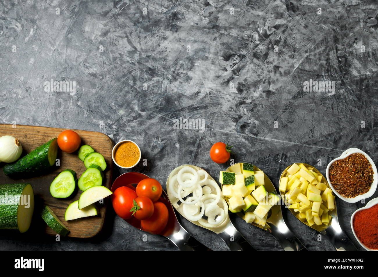 Verdure sullo sfondo. Ortaggi freschi (cetrioli, pomodori, cipolle, aglio, aneto, fagioli verdi) su sfondo grigio. A Foto Stock