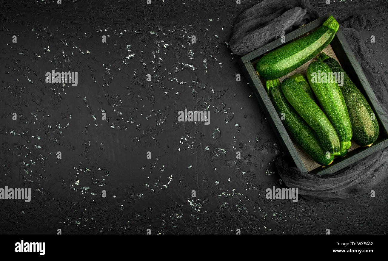 Fresco verde di zucchina al buio su un tavolo. La vista dall'alto. Copia dello spazio. Foto Stock