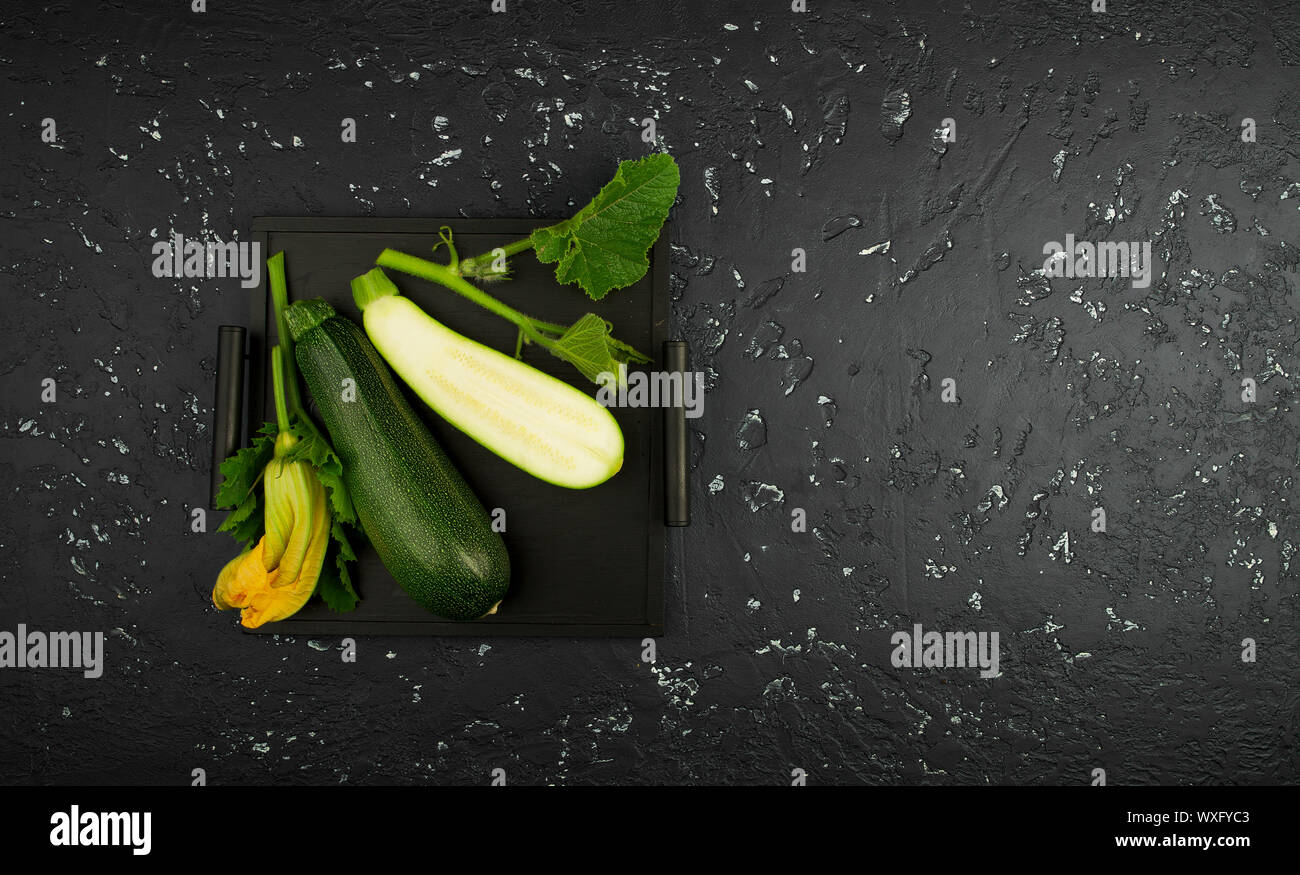 Fresco verde di zucchina al buio su un tavolo. La vista dall'alto. Copia dello spazio. Foto Stock