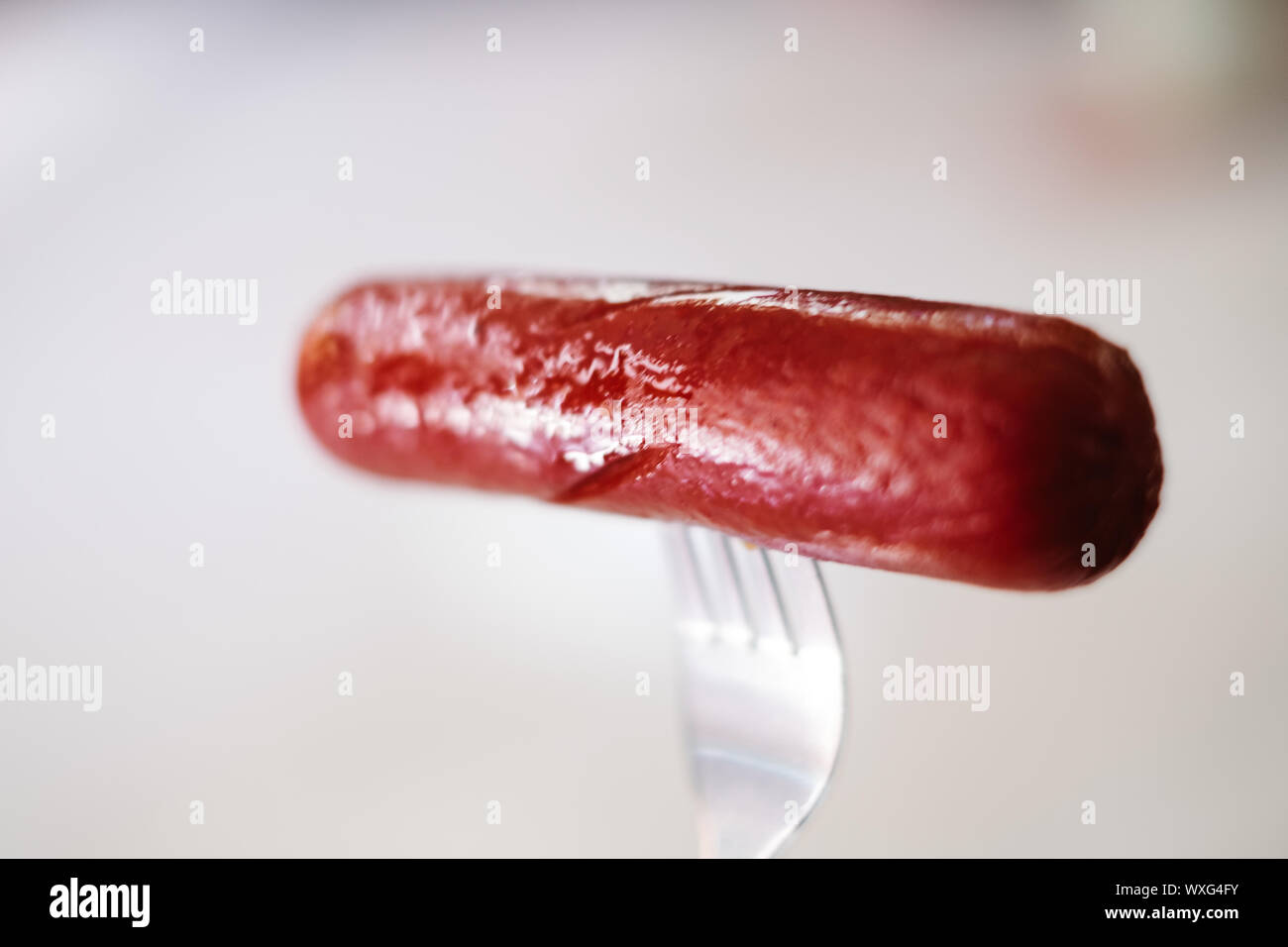 Velocemente e facilmente cuocere hotdog in una forcella per la prima colazione, su sfondo bianco. Messa a fuoco selettiva. Copia dello spazio. Foto Stock