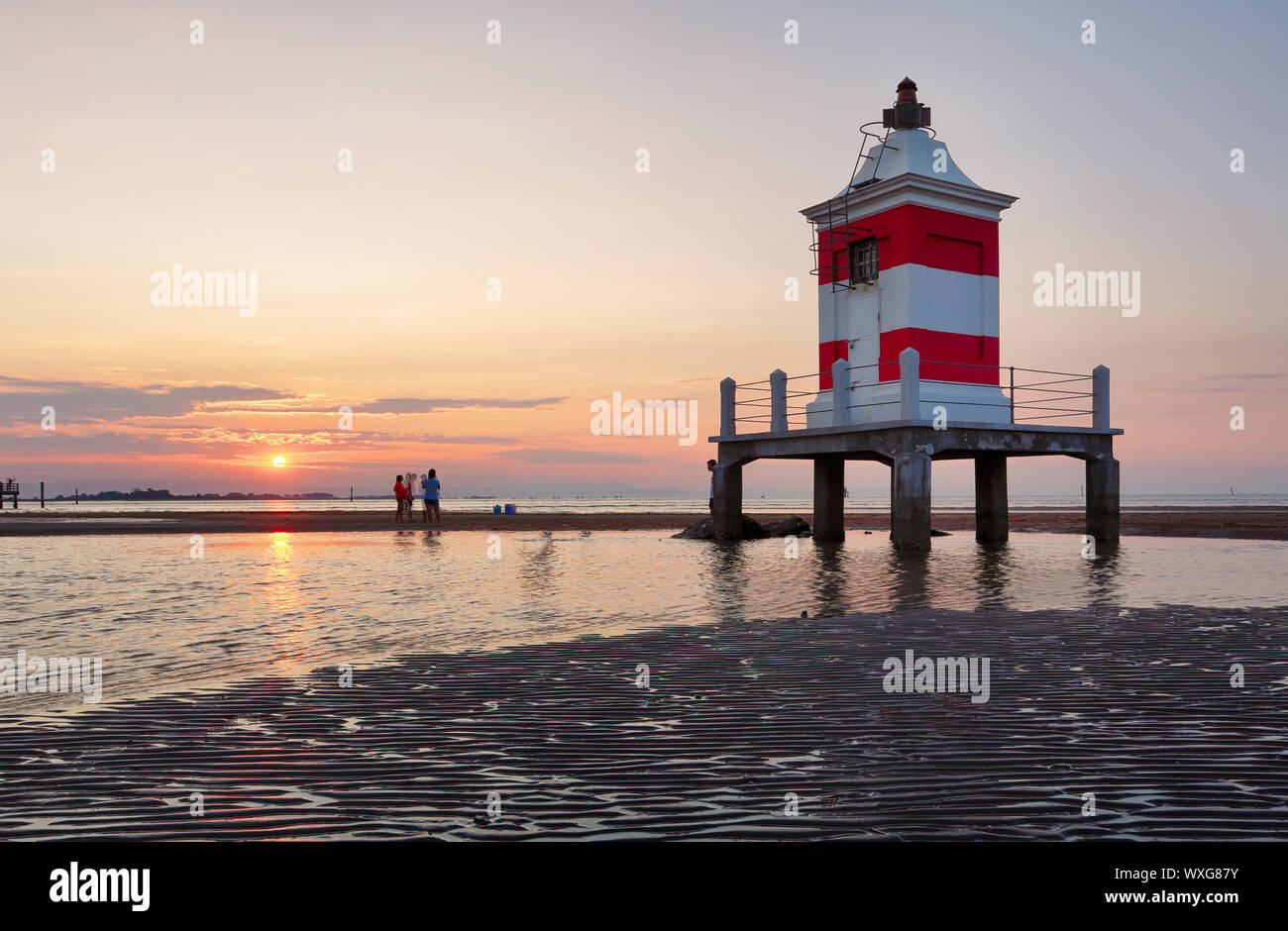 Faro al tramonto in Italia con la spiaggia Foto Stock