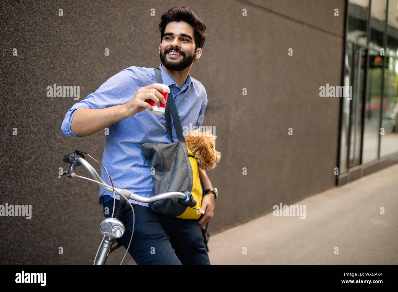Giovane uomo di bere il caffè mentre è seduto sulla sua bicicletta con il cane all'aperto Foto Stock