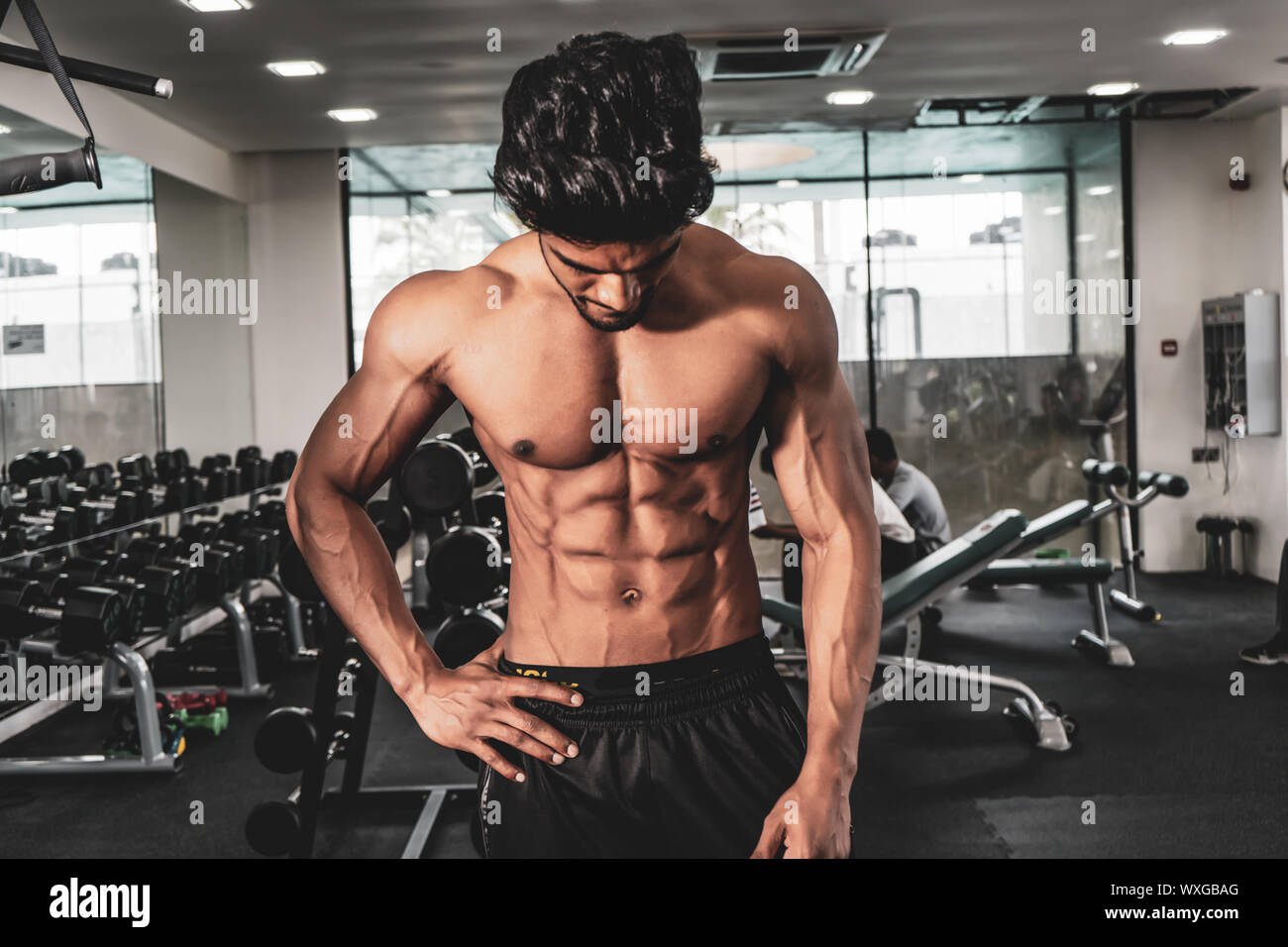 Uomo bello con grandi muscoli, che pongono la fotocamera in palestra Foto Stock