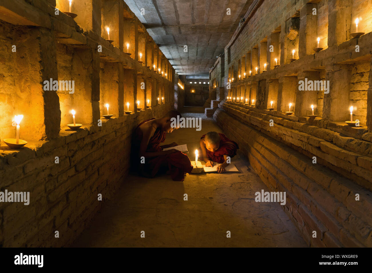 Il debuttante i monaci buddisti studiano all'interno di antico tempio pagoda a lume di candela Foto Stock