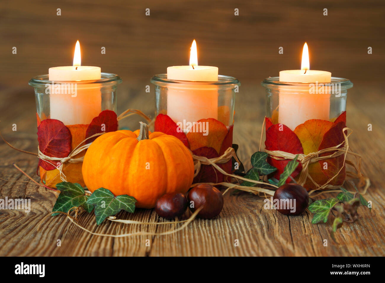 Decorazione autunnale con candele accese, castagne e una piccola zucca. Svizzera Foto Stock