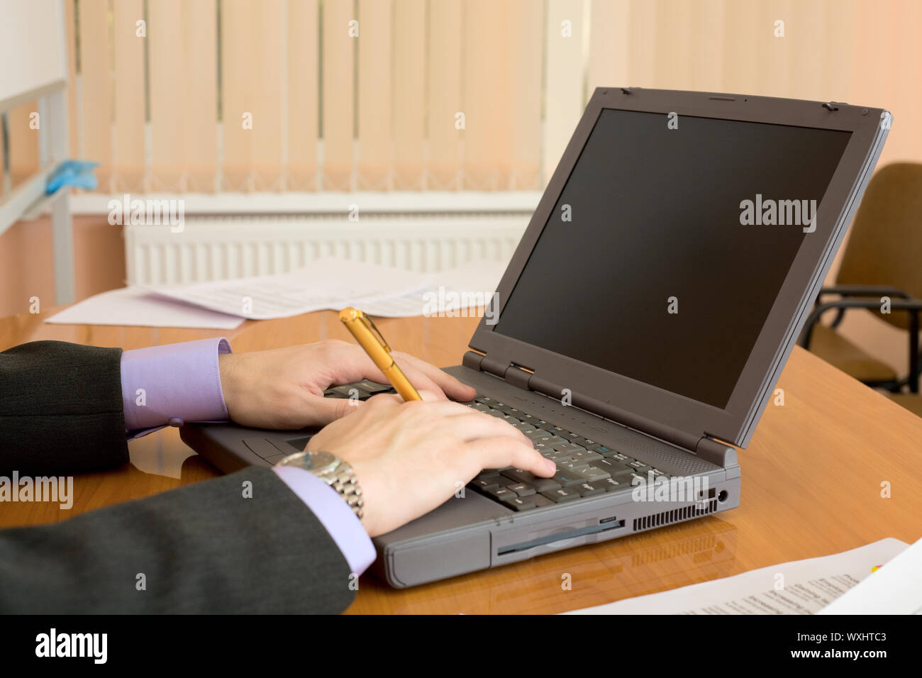 Il laptop e mani dell'uomo con una penna Foto Stock