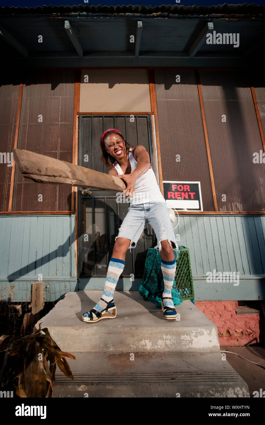 African American donna oscillazione un bordo sul suo portico anteriore Foto Stock