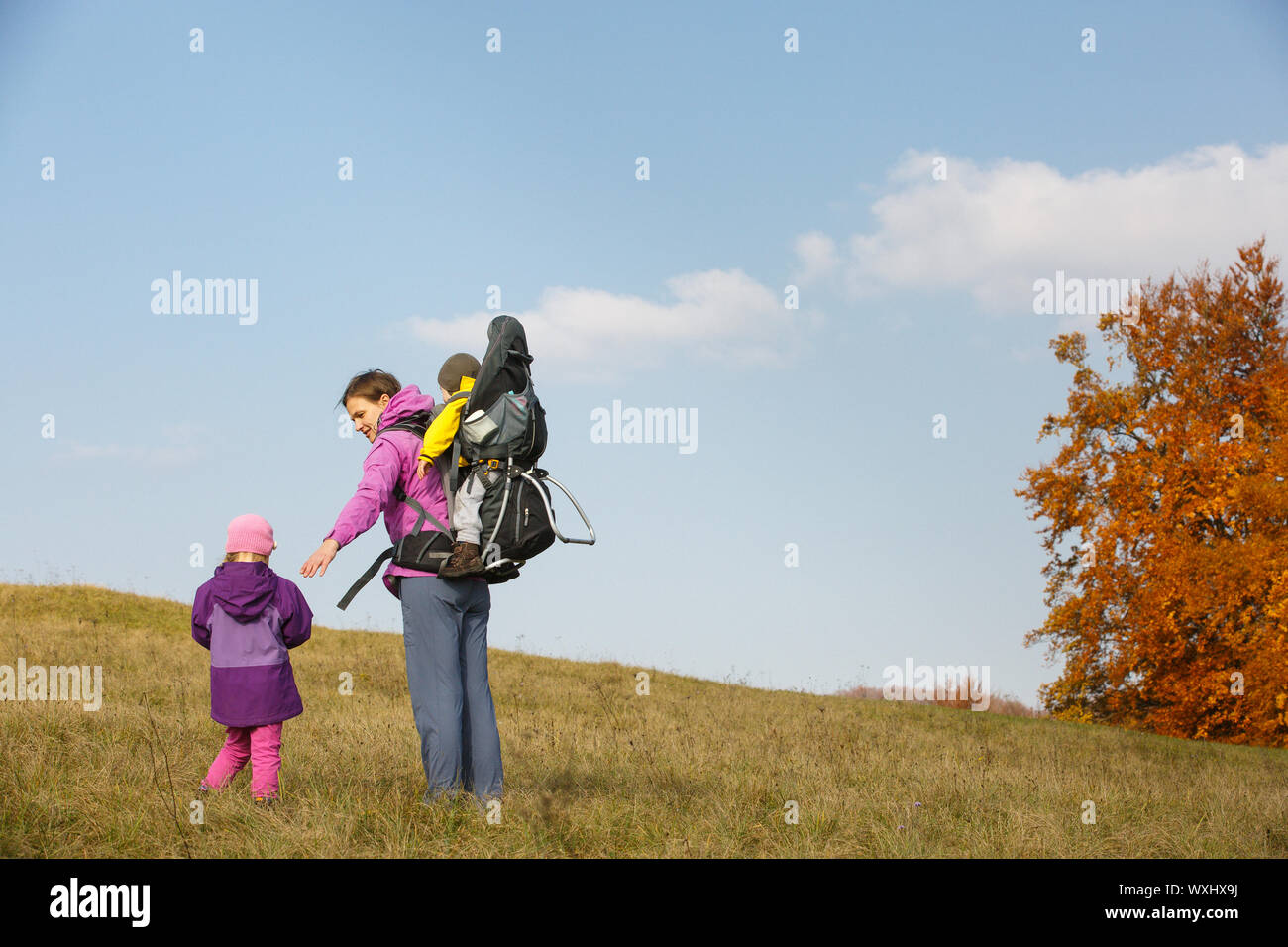 Madre con bambini in natura in una bella giornata autunnale che trasportano kid Foto Stock