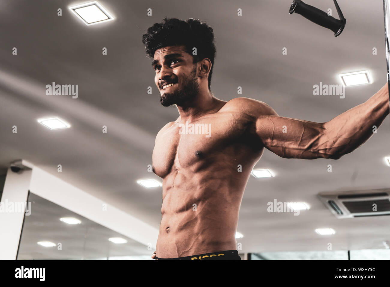 Uomo bello con grandi muscoli, che pongono la fotocamera in palestra Foto Stock